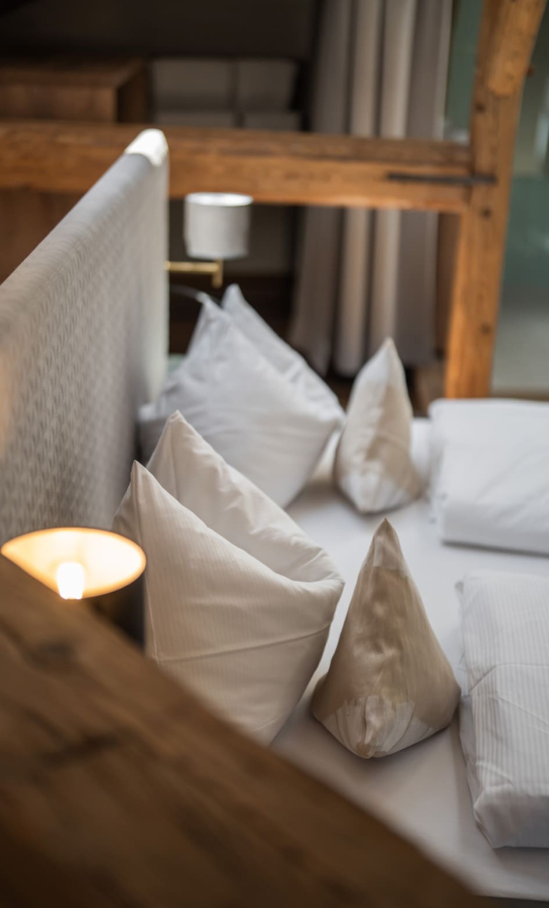 Gemütliches Schlafzimmer mit Holzbalken, Dachfenster und modernem Bett