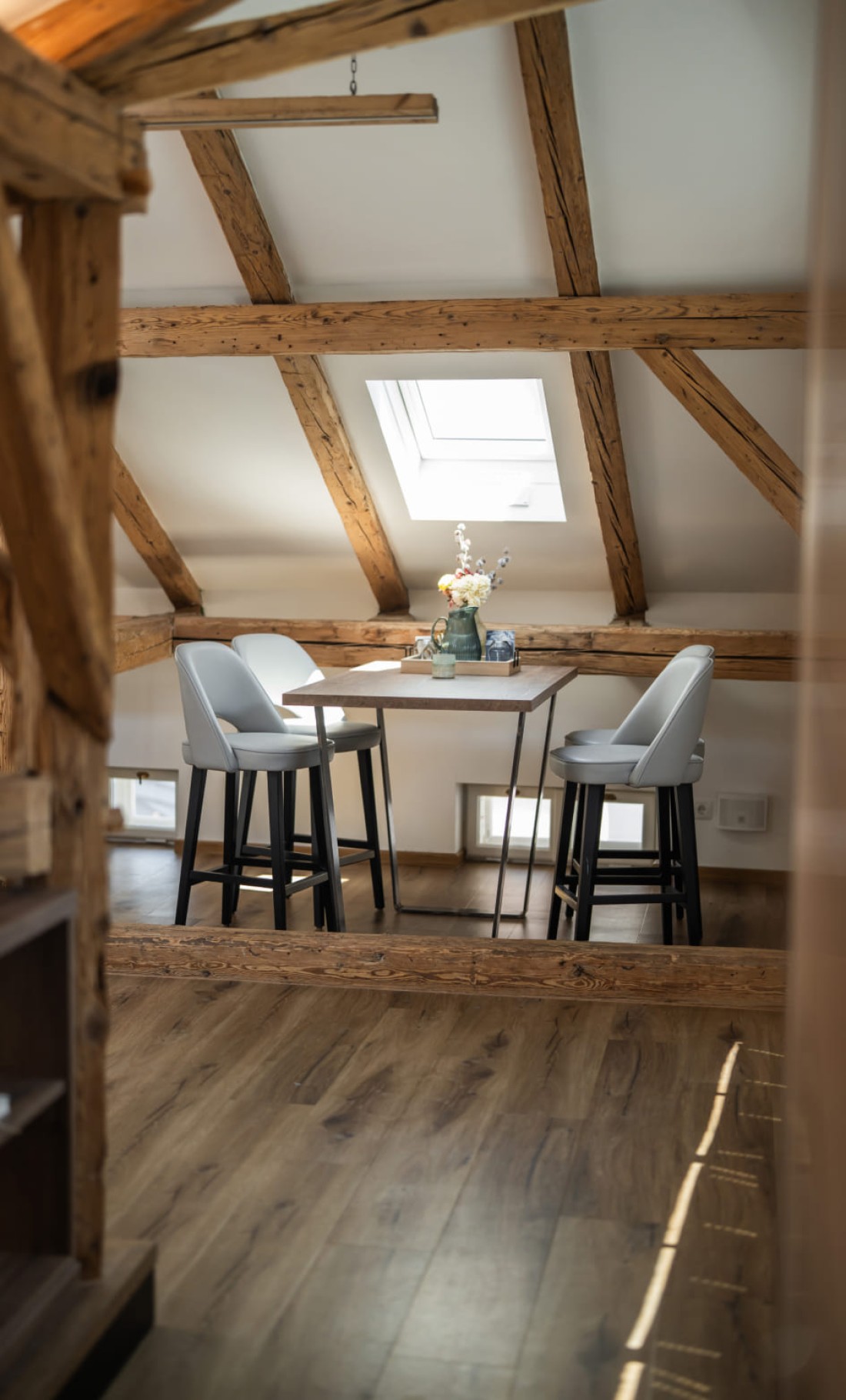 Essbereich der Loft Suite mit freiliegenden Holzbalken und Dachfenster